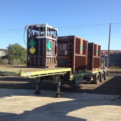 Flatbed trailer carrying tanks with hazard placards